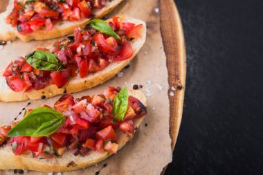 İtalyan yemeği aperatifi, domatesli bruschetta ve tahtada fesleğen.
