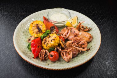 Restoran masasında sebzeli ızgara kalamar yemeği. Lezzetli deniz ürünleri.