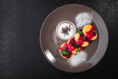 Süzme peynirli gözleme, kırmızı reçel ve böğürtlen restoran masasında.