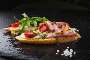 Domates ve pastırmalı aperatif bruschetta, siyah tahtada satranç.