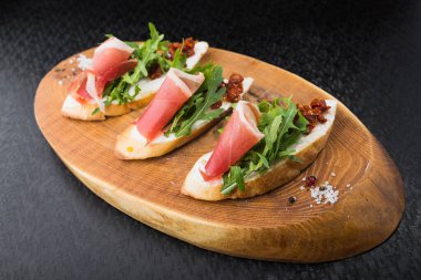 Domates ve pastırmalı aperatif bruschetta, tahtada satranç.