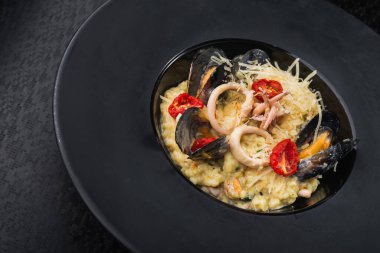 Siyah tabakta deniz ürünleri, midye, mürekkep balığı ve İtalyan peyniri ile risotto. Restoran servis yemekleri