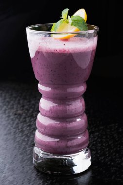 Smoothie yabanmersini içeceği, siyah arka planda bardakta.