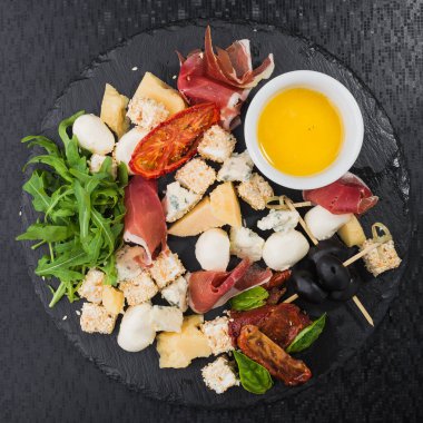 Peynir, jambonlu yemek ve domates, siyah tahta.