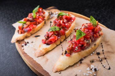 İtalyan yemeği aperatifi, domatesli bruschetta ve tahtada fesleğen.