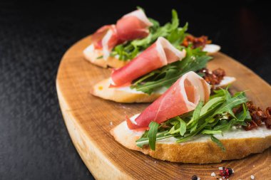 Domates ve pastırmalı aperatif bruschetta, tahtada satranç.