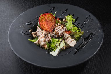 Lezzetli salata, dana eti ve siyah tabakta domates, koyu masa. restoran yemeği