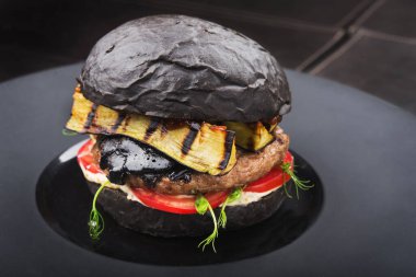 Lezzetli siyah burger, biftek ve tabakta yeşil salata, restoranda atıştırmalık.