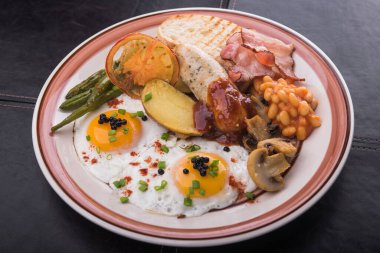 Yumurta, domuz sosisi, fasulye, mantar ve pastırma kahvaltısı. Restoranda doyurucu bir kahvaltı.