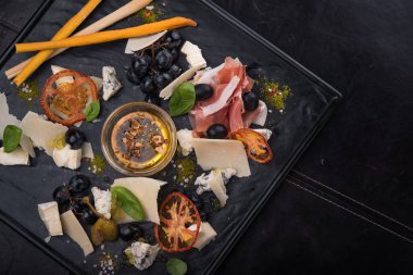 Lezzetli peynirli sos, prosciutto ve siyah tahtada üzümler. Lokanta Foo