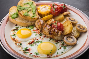 Yumurtalı, domatesli ve patatesli kahvaltı. Siyah masada lezzetli bir öğle yemeği.