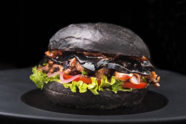 Lezzetli siyah burger, biftek ve tabakta yeşil salata, restoranda atıştırmalık.