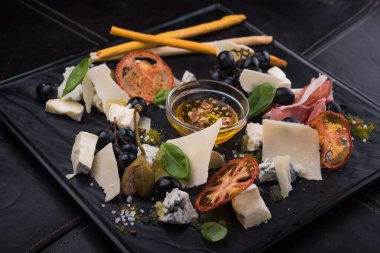 Lezzetli peynirli sos, prosciutto ve siyah tahtada üzümler. Lokanta Foo