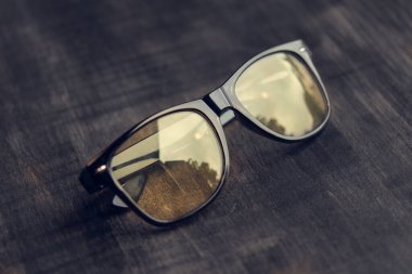 Tahta masaya yansıyan siyah gözlükler. 