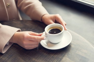 Masasında beyaz kahve fincanı olan bir kadın. İş kadınının yaşam tarzı. Restoranda kahvaltı.