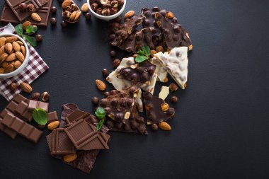Siyah arka planda fındıklı siyah beyaz çikolata, taze nane ve badem.
