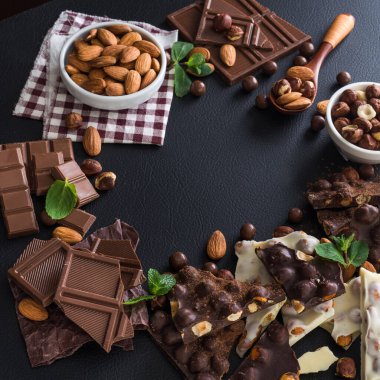 Siyah arka planda fındıklı siyah beyaz çikolata, taze nane ve badem.