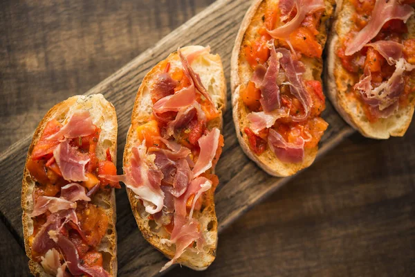 Köstliche Italienische Bruschetta Mit Tomaten Und Prosciutto Auf Einem Holztisch — Stockfoto