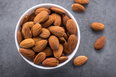 Taş masada beyaz bir tabakta badem fıstığı.