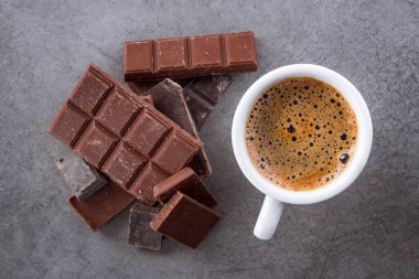 Aroma kahve fincanı, üzerinde çikolata bardakları olan taş bir masa.