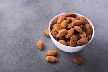 Taş masada beyaz bir tabakta badem fıstığı.
