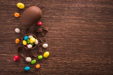 Paskalya tatlısı lezzetli çikolatalı yumurta ve ahşap masa üzerinde renkli şeker sürahisi.