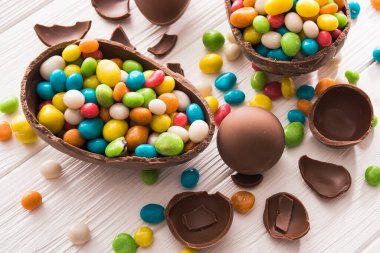 Paskalya tatlısı lezzetli çikolatalı yumurta ve ahşap masa üzerinde renkli şeker sürahisi.