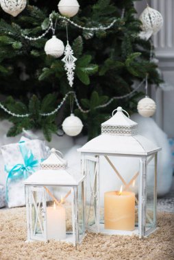 Noel ağacı, ahşap fener şamdanı, mumlar ve Noel ağacı, arka planda hediyeler.