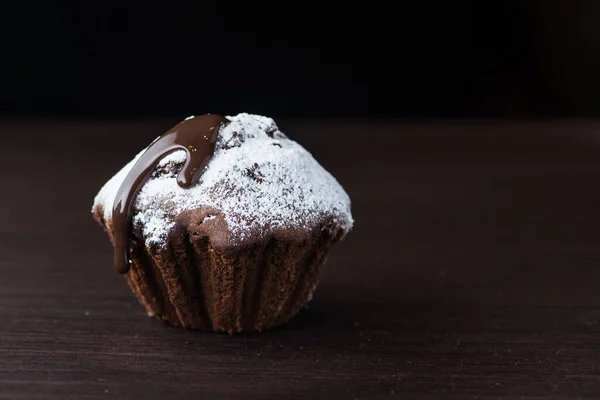 黒テーブルの上に粉入りの甘いチョコレートケーキ — ストック写真