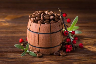Kahverengi doğal masada, ahşap bir fıçıda kavrulmuş kahve çekirdekleri.