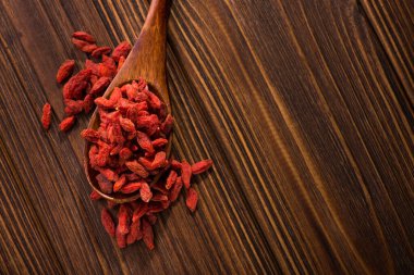 Tibet goji üzümleri, yukarıdan bakıldığında, ahşap masada birçok yararlı madde, vitamin ve mineral içerir.