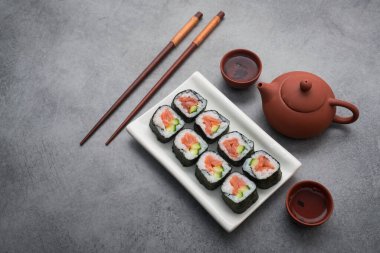 Suşi somon ve salatalıklı çay seremonisi, gri taştan bir masada.