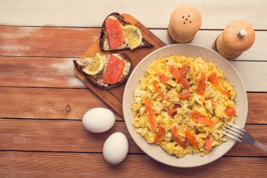 Somon balığı, yumurta, ahşap bir masada limonlu bruschetta ile çırpılmış kahvaltı. Yukarıdan bak. Kırsal gıda tarzı