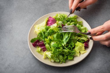 Kadın marul ve roka içeren vejetaryen yemeği yiyor. en üstteki görünüm