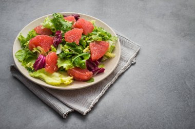 Marullu taze salata, yeşil roka ve taş masada dilimlenmiş greyfurt. diyet yemeği