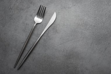 Taş bir masada metal çatal ve bıçak. en üstteki görünüm