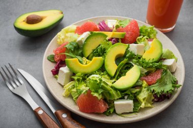 Salata ve sebzelerden yemek yemek ve taş bir masada avokado yemek. diyet zamanı