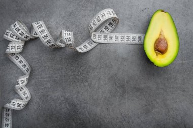 Taze avokado meyvesi ve arka planda beyaz mezura. Konsept diyet. Üst görünüm