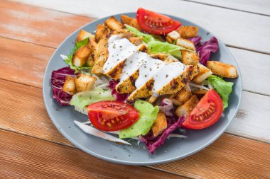 Izgara tavuklu taze salata, domates, tahta masada kraker ekmeği. sağlıklı renkli yiyecekler