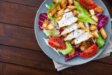 Izgara tavuklu taze salata, domates, tahta masada kraker ekmeği. sağlıklı renkli yiyecekler