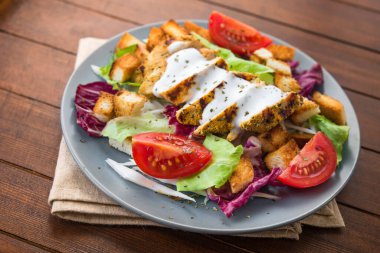 Izgara tavuklu taze salata, domates, tahta masada kraker ekmeği. sağlıklı renkli yiyecekler