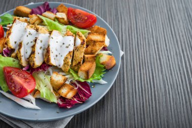 Izgara tavuklu taze salata, domates, tahta masada kraker ekmeği. sağlıklı renkli yiyecekler