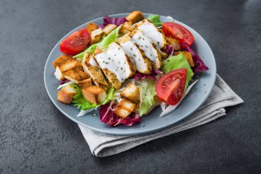 Kızarmış tavuklu taze salata, domates, taş masada kraker. sağlıklı akşam yemeği