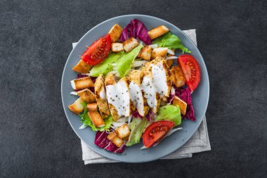 Kızarmış tavuklu taze salata, domates, taş masada kraker. Sağlıklı yemek. en üstteki görünüm