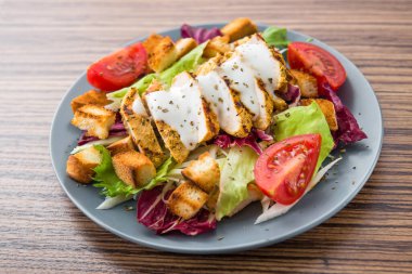 Tavuk fileto ve ahşap bir masada sebzeli taze salata. Lezzetli ve sağlıklı kahvaltı.