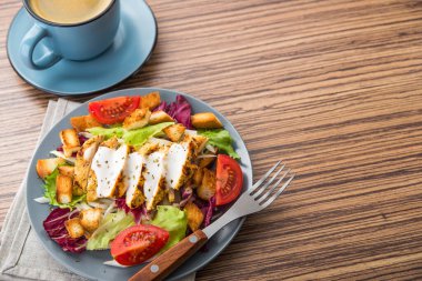 Tahta bir masada mavi kahve fincanı ile taze tavuk salatası. İştah açıcı yemek geçmişi