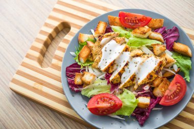 Tavuk fileto ve ahşap bir masada sebzeli taze salata. Lezzetli ve sağlıklı kahvaltı.
