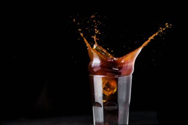 Siyah bir fonda koyu buzlu kahve sıçradı.