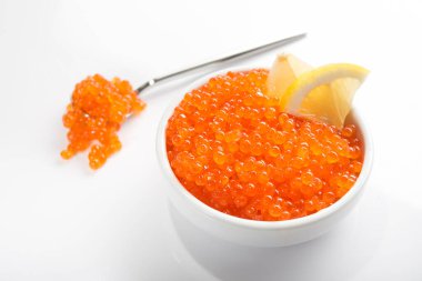 Kırmızı havyar beyaz arka planda izole edilmiş bir kasede limon dilimler..