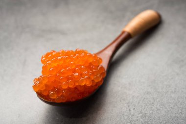 Arka planda kırmızı havyar olan bir kaşık. Aperatif deniz ürünleri